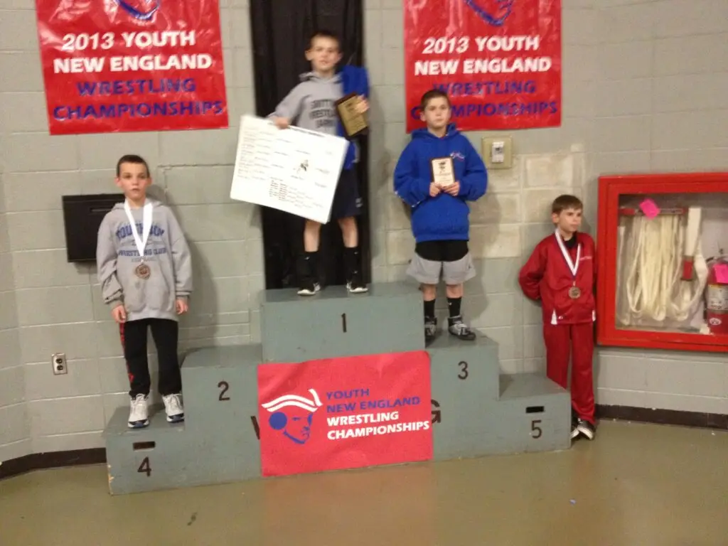 Youth wrestler on medal podium at a New England wrestling tournament awards ceremony